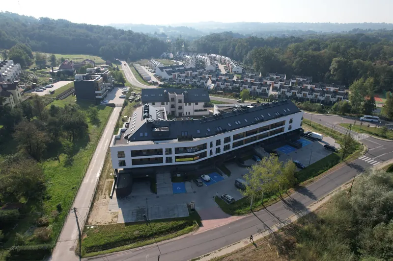 Budynek w otoczeniu zieleni i nowej zabudowy